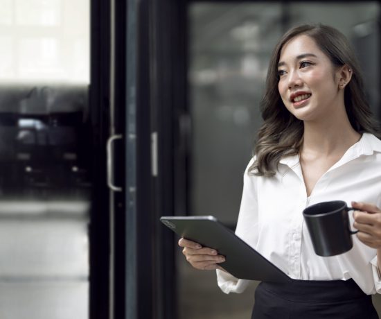 portrait-young-smiley-asian-businesswoman-holding-tablet-mug-standing-modern-officer-scaled.jpg