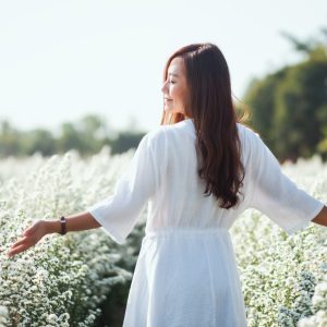 rear-view-woman-with-arms-outstretched-standing-amidst-flowers-scaled.jpg